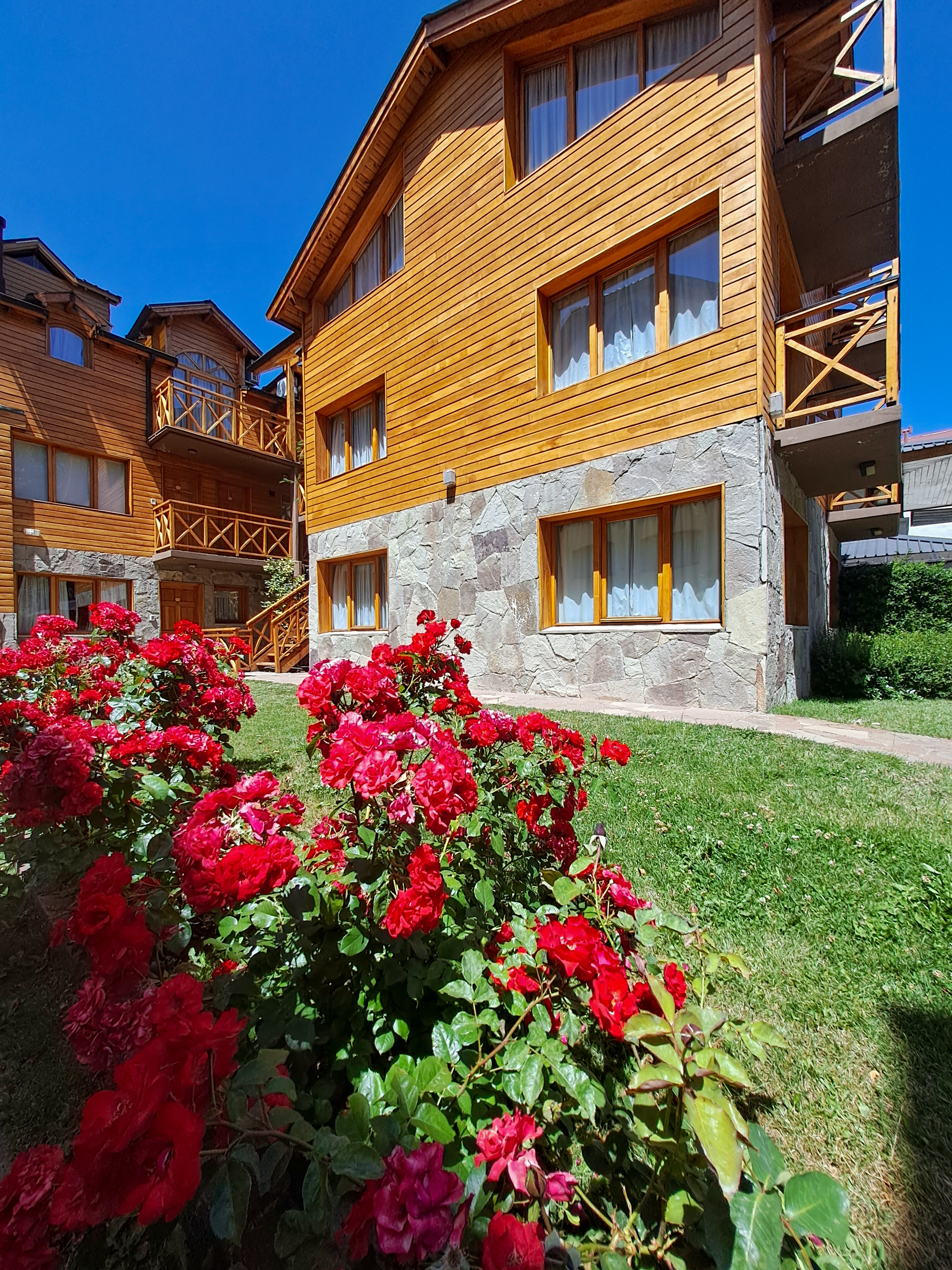 Fachada de piedra y madera con jardín de rosas